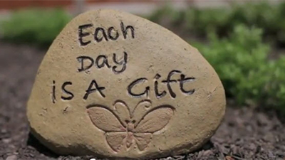 Engraved rock in the garden with the phrase Each Day is a Gift