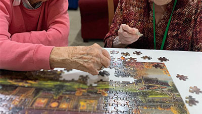 Two elderly memory care residents piecing together a puzzle