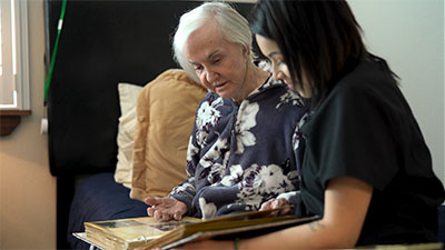Elderly memory care resident looking through photo album with caregiver