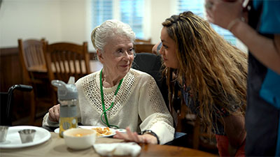 Memory care resident eating breakfast with caregiver