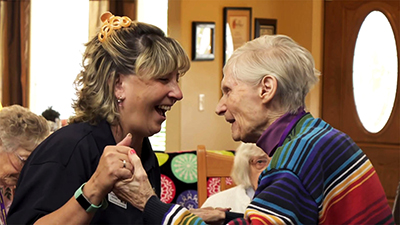 Happy caregiver dancing with elderly memory care resident