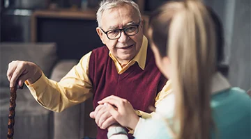 Elderly gentleman converses with attentive caregiver