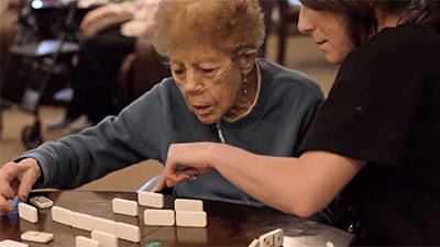Elderly woman plays game with caregiver