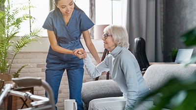 Caregiver assists a woman to stand
