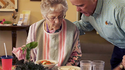 Caregiver offering dinner to senior resident