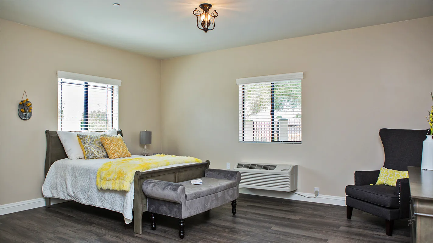 Private resident bedroom with warm yellow accents and a comfortable bed