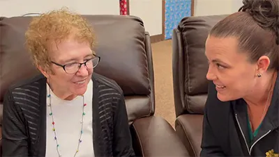 An older woman smiling with a caregiver