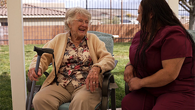 Senior lady sitting outside with compassionate caregiver