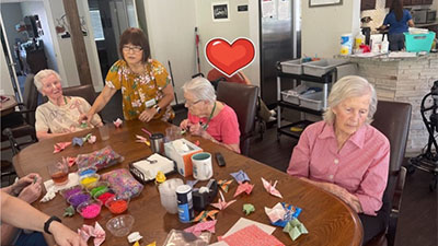 Senior memory care residents crafting around the table together