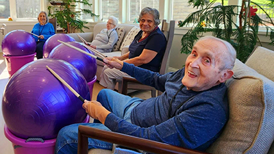 Residents play music with exercise balls and drum sticks