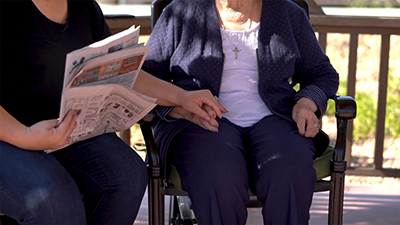 Elderly woman and caregiver sit outside